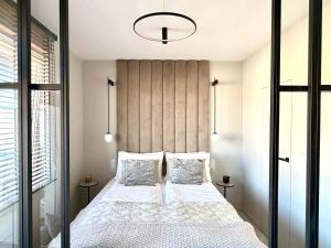 a bedroom with a bed with white sheets and pillows at Apartamant Oaza II in Koszalin