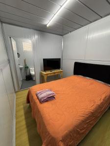 a bedroom with an orange bed and a television at Amanecer Rio Limay 2 in Plottier