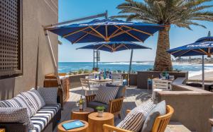restauracja z niebieskimi parasolami i plażą w obiekcie Strand Hotel Swakopmund w mieście Swakopmund