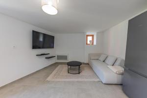 a white living room with a couch and a tv at Le Gerbolle in Reventin-Vaugris