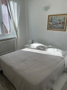 a white bed in a bedroom with a picture on the wall at Casa Viorica in Ancona