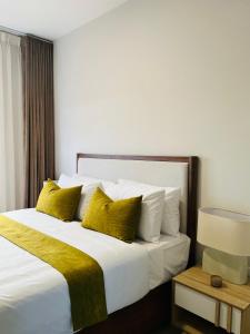 a bedroom with a large white bed with yellow pillows at The Kgale Luxe in Gaborone