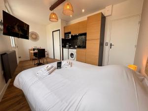 a large white bed in a room with a kitchen at 2 Neufchâtel studio agréable et cosy tout équipé in Reims