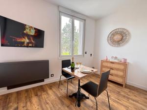 a dining room with a table and a tv at 2 Neufchâtel studio agréable et cosy tout équipé in Reims +12 photos