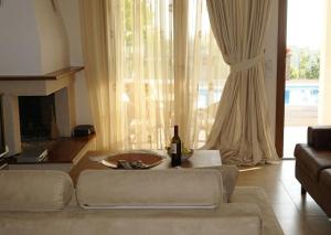 a living room with a couch and a table with a bottle of wine at Cave Luxury Villas Skiathos in Troulos
