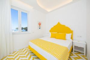 a white bedroom with a yellow and white bed at Palazzo Sant'Elena in Anacapri