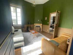 a living room with green walls and a couch at Le Louis d'Or in Beaumont-sur-Sarthe