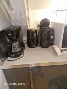 eine Theke mit drei Kaffeekannen und Pfannen darauf in der Unterkunft Orléans Appartement 2 chambres avec Parking in Orléans