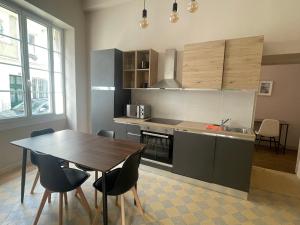 a kitchen with a table and a table and chairs at Le Louis d'Or in Beaumont-sur-Sarthe