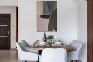 a dining room with a table with chairs and a painting at Kraken 2-BR Apartment by Makenzy Beach in Larnaca +8 photos