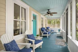 a porch with blue chairs and a ceiling fan at Cabin in Tybee Island, Georgia in Tybee Island
