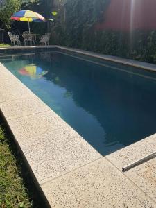 a swimming pool with a table and an umbrella at Wisla Rellowed in Manuel B. Gonnet +10 photos