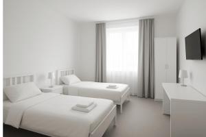 a white hotel room with two beds and a tv at Hannover Group Apartment in Hannover