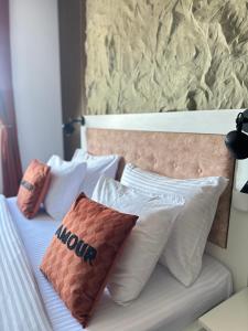 a bed with white pillows on it with a wall at Apartman Viktorija in Žabljak