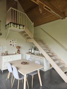 a kitchen with a table and a wooden staircase at B&B Chocla-dort in Koekelare