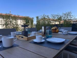 a wooden table with cups and plates on it at Casa Chiaretto Piscina e Relax nel cuore di Moniga in Moniga