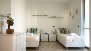 a white room with two beds and a table at Casa Chiaretto Piscina e Relax nel cuore di Moniga in Moniga +29 photos