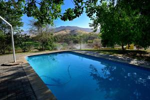 a blue swimming pool with mountains in the background at Uitkyk Guest Farm in Usakos