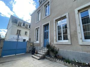 a house with a blue gate in front of it at Le Louis d'Or in Beaumont-sur-Sarthe