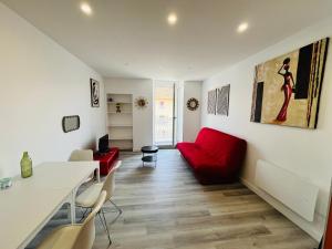 a living room with a red couch and a table at Le Vinois Climatisation 2 chambres balcon in Vinay