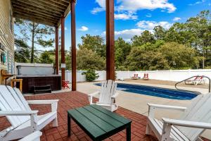 a patio with white chairs and a swimming pool at Rising Sun OBX in Corolla