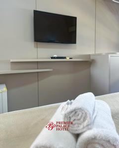 a room with a tv and a bed with a towel at Premier Palace Hotel in Araranguá