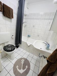 a bathroom with a toilet and a sink with an anchor on the floor at Haus Larum App. 3 in Scharbeutz +40 photos