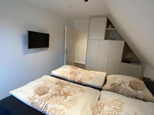 a bedroom with two beds and a tv on the wall at Haus Larum App. 6 in Scharbeutz