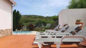 a row of lounge chairs on a patio with a pool at Casa do Mar - Lagoa de Óbidos, T3, piscina, vista lagoa in Vau