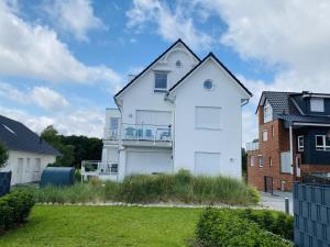 a white house with a balcony in a yard at Meersicht Haffkrug in Haffkrug