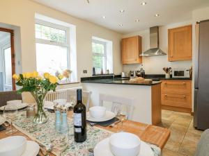 a kitchen with a table with a bottle of wine at Lumford Mill Cottage in Bakewell