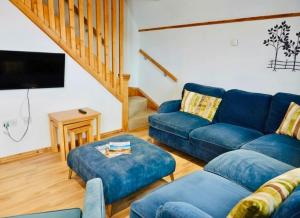a living room with blue couches and a tv at Primrose Lodge with Hot Tub near Waterpark and Trails in Chudleigh +72 photos