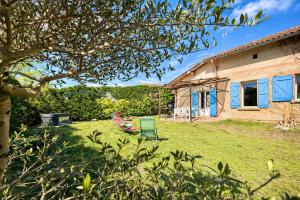 a yard with a house and a green chair at " Verdun Paradise " Jardin - Salle de Sport - Salle de Jeux in Verdun-sur-Garonne