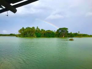 a rainbow over a body of water with trees at Ela addara Home stay in Lukasgoda
