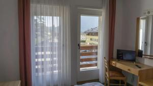 ein Zimmer mit einem Schreibtisch, an dem ein Computer steht, und einem Fenster in der Unterkunft Hotel Ideal in Sarche di Calavino