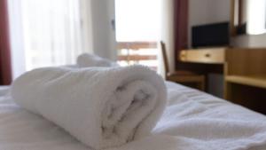 Ein weißes Handtuch liegt auf einem Bett. in der Unterkunft Hotel Ideal in Sarche di Calavino