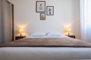 a bedroom with a large bed with two lamps at À 300m du virage de Mulsanne - Maison 8 pers avec extérieur et parking in Mulsanne