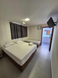 a bedroom with two beds and a television in it at Apart Suítes Praia Do Morro 5 a 7 dias e Barato in Guarapari