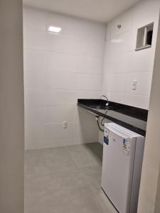 a small kitchen with a counter and a refrigerator at Apart Suítes Praia Do Morro 5 a 7 dias e Barato in Guarapari