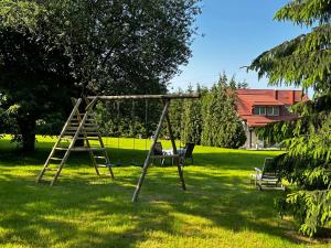 a swing set in a yard with a tree at Villa van Dam in Miłków