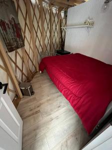 a red bed in a room with a wooden floor at Havre du Lac Montagnais in Saint-Fulgence