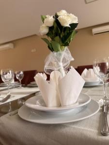 a table with a plate with a vase of white roses at Hotel BlueTwo Međugorje in Međugorje