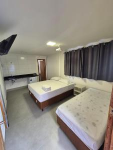 a bedroom with two beds and a television in it at Suites Casal Com AR Semanal ou 7 dias E BARATO in Guarapari +10 photos
