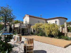 a large white house with chairs in a yard at La Closerie in Laredorte