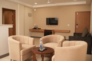 a living room with two chairs and a tv at Hotel Bariz Perinthalmanna in Perintalmanna