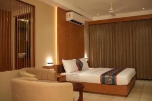 a hotel room with a bed and a chair at Hotel Bariz Perinthalmanna in Perintalmanna +44 photos