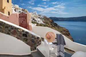 a hat on a bench on a balcony overlooking the ocean at HIDEAWAY CAVE HOUSE in Oia
