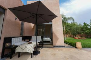 a patio with an umbrella and a table and chairs at Dar El Gharrabia villa entièrement privatisée in Amezrou