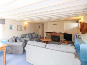 a living room with white furniture and a fireplace at Orchard Barn in Salcombe
