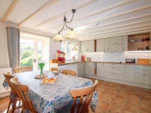 a kitchen with a table and chairs and a kitchen with white cabinets at Orchard Barn in Salcombe